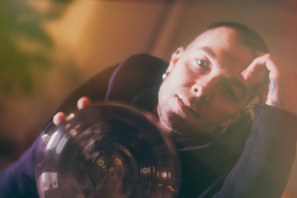 Jeramie Bellmay with soft moody side light holding a distorted crystal sphere that looks like a portal