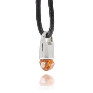 Side view of necklace with a silver and garnet crystal pendant on a black cord against a white background